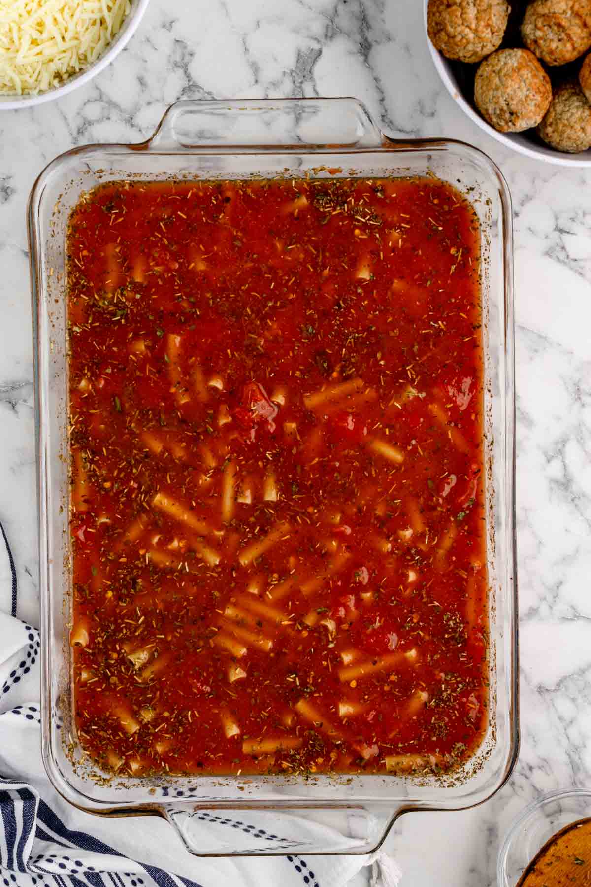 uncooked ziti in stock and pasta sauce mixture in a baking dish