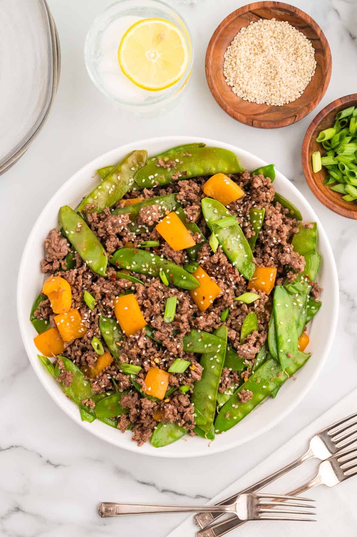 Ground Beef Stir Fry is an easy weeknight dinner recipe loaded with ground beef, snow peas, orange bell pepper, green onions and sesame seeds all cooked in a garlic, ginger, honey and soy sauce mixture.