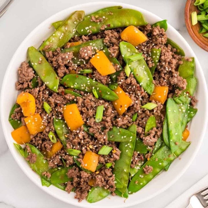 Ground Beef Stir Fry is an easy weeknight dinner recipe loaded with ground beef, snow peas, orange bell pepper, green onions and sesame seeds all cooked in a garlic, ginger, honey and soy sauce mixture.