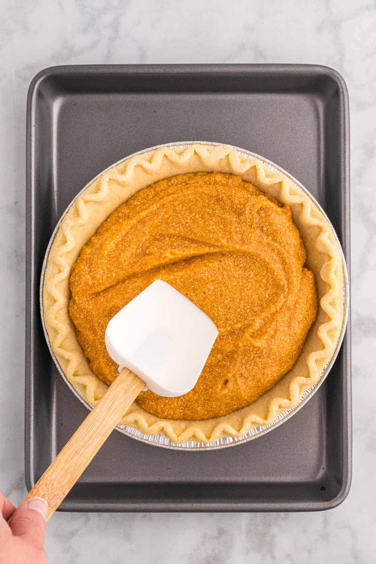 sweet potato mixture being spread in a pie crust