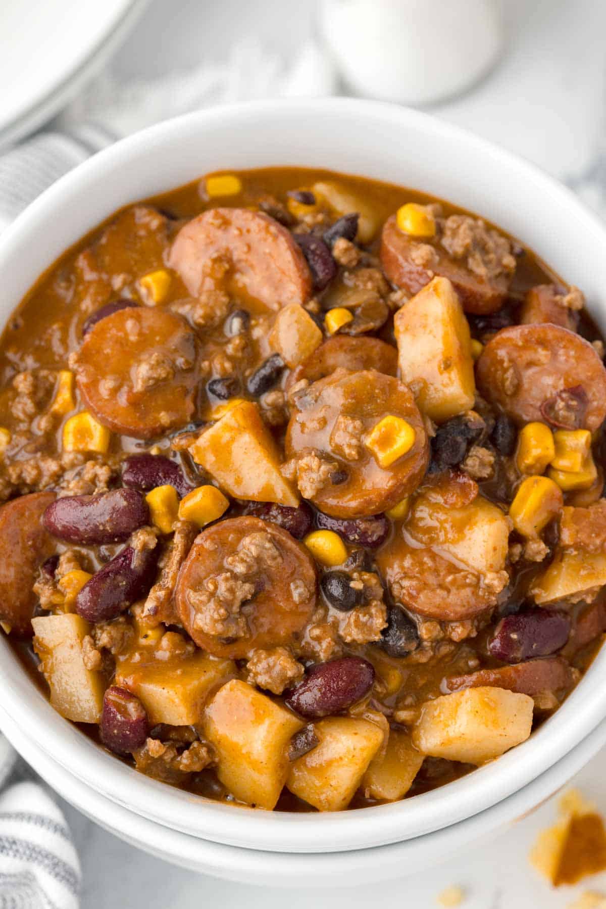 Texas Cowboy Stew is a hearty dish loaded with ground beef, smoked sausage, bacon, potatoes, corn, beans and diced tomatoes all in a flavourful beef broth.