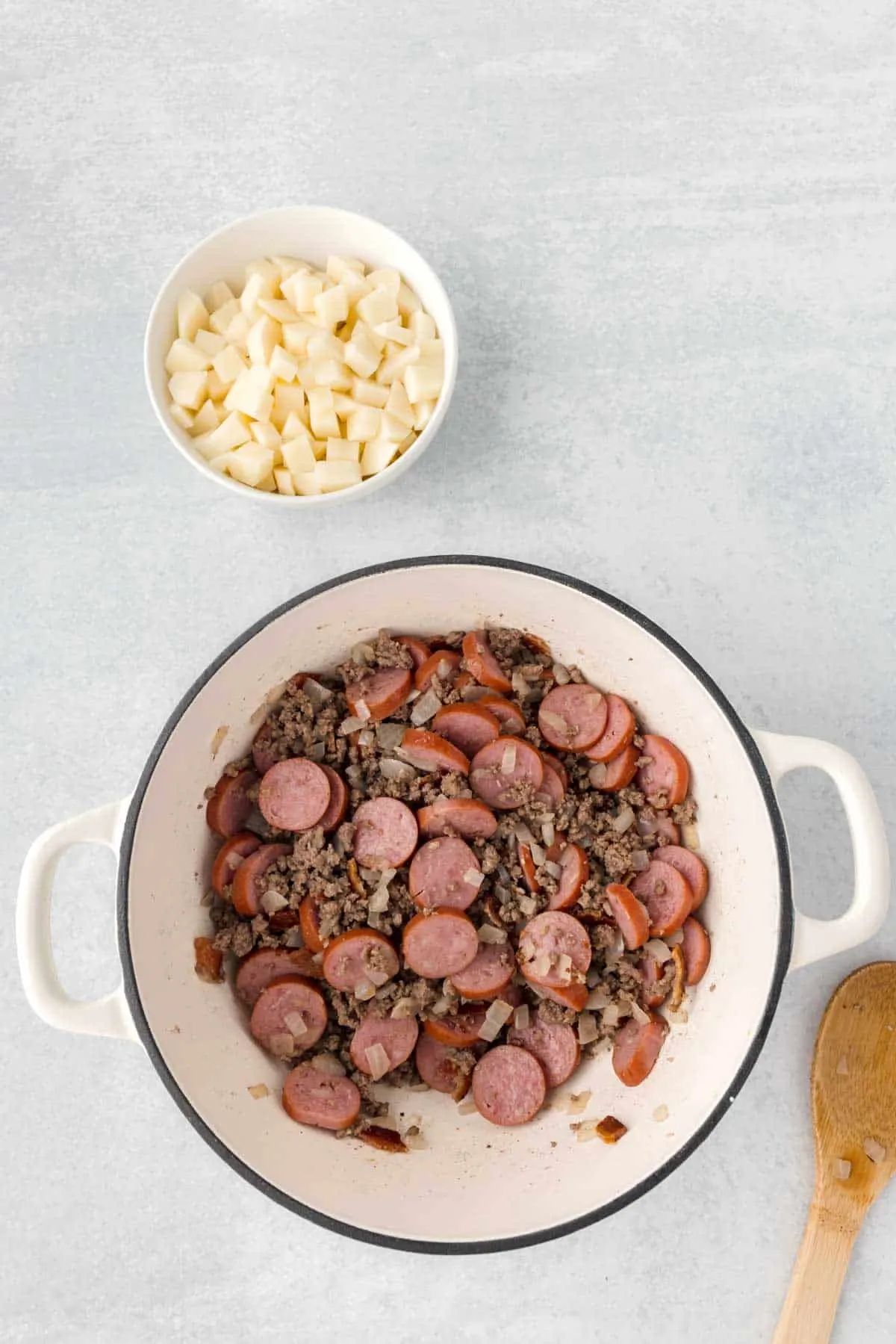 cooked ground beef, crumbled bacon and sausage slices stirred together in a Dutch oven