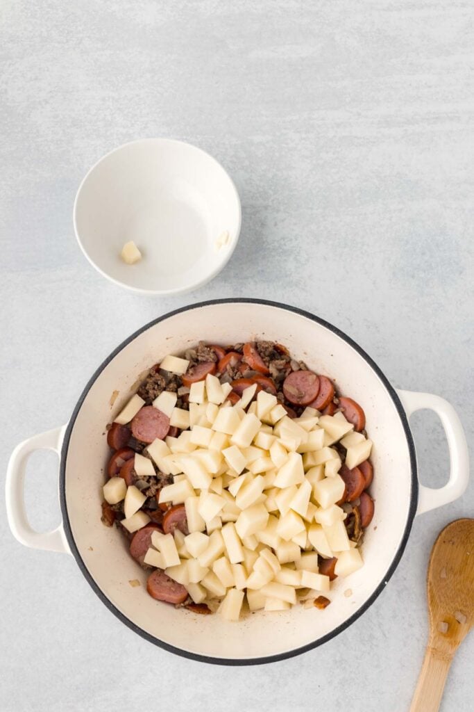 diced potatoes added to Dutch oven with cooked ground beef and smoked sausage slices