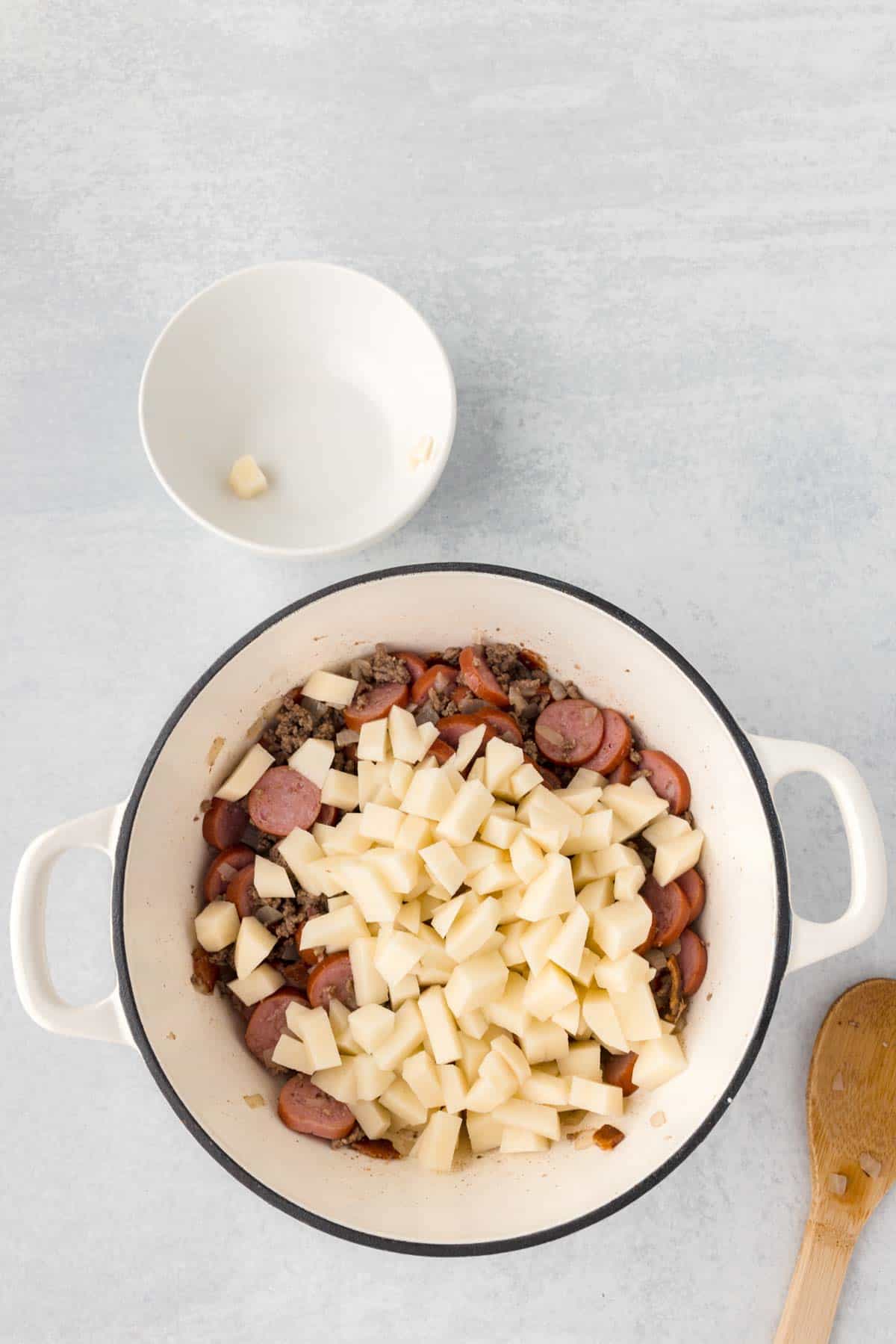 diced potatoes added to Dutch oven with cooked ground beef and smoked sausage slices