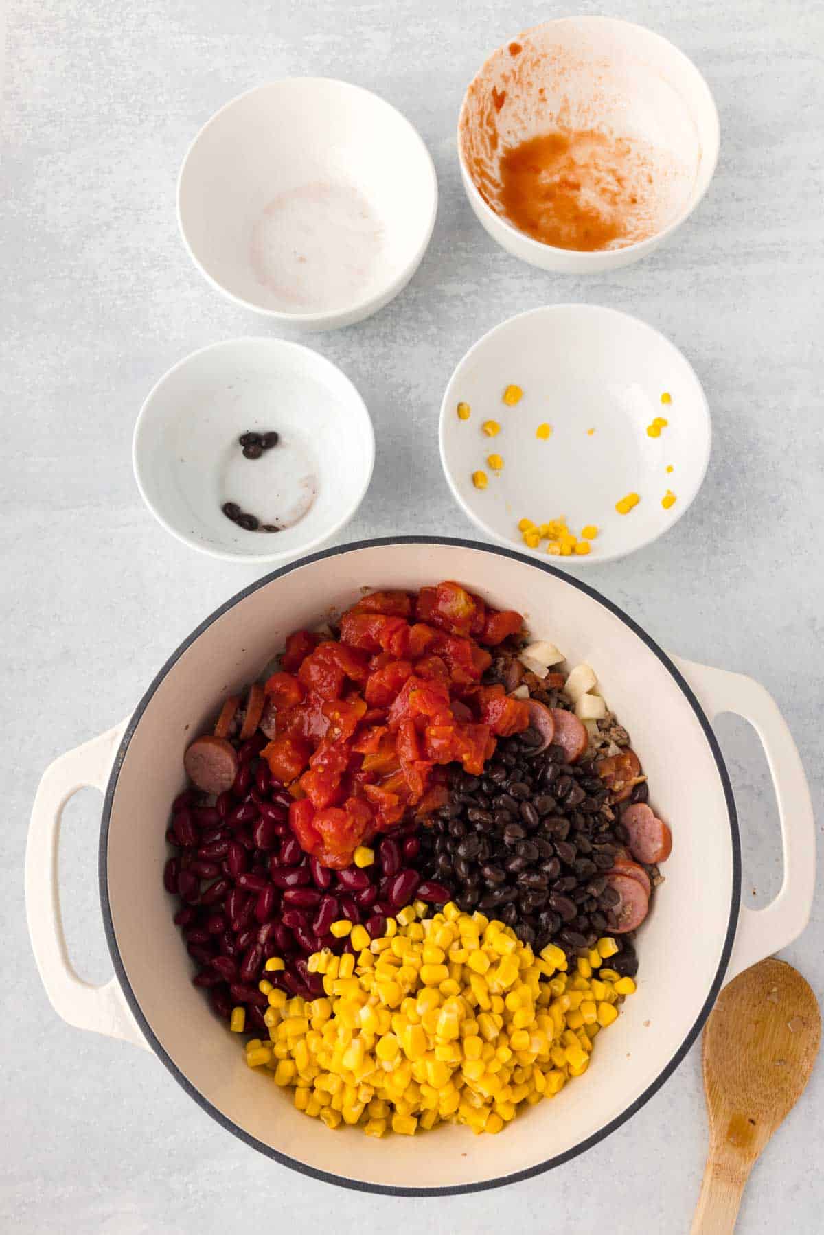 diced tomatoes, kidney beans, black beans and corn on top of ground beef and sausage in a Dutch oven