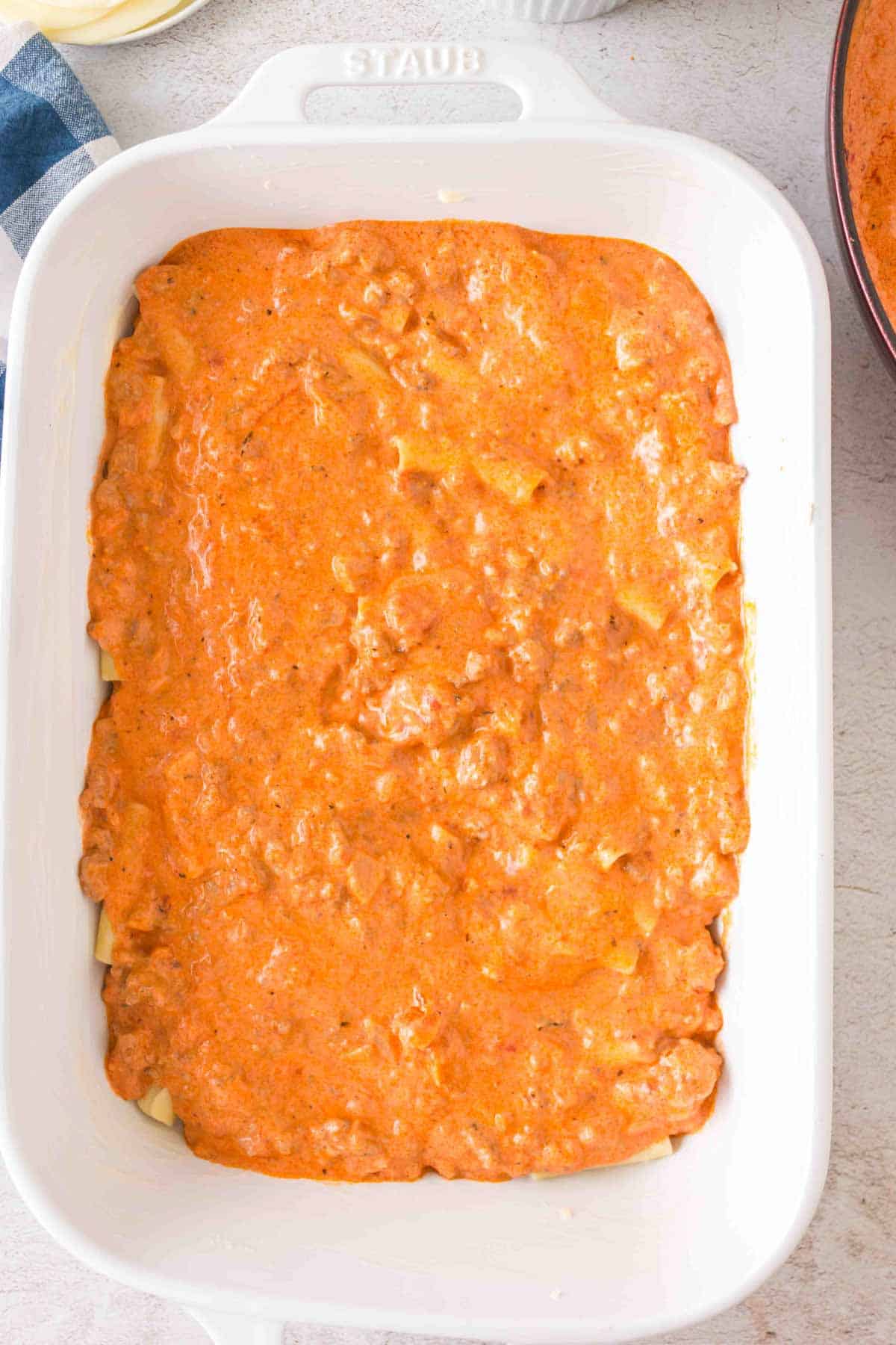 meat sauce over ziti noodles in a baking dish