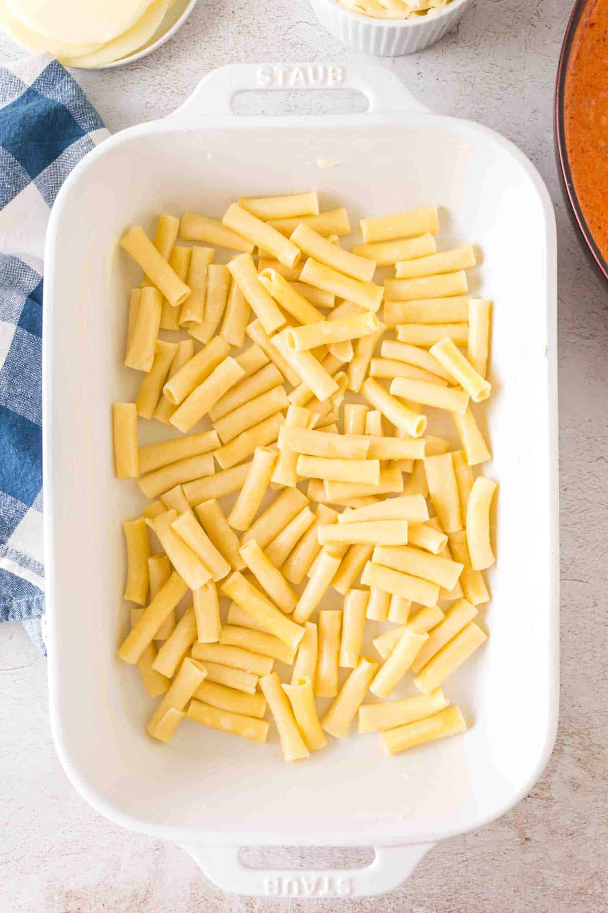 cooked ziti noodles in the bottom of a baking dish