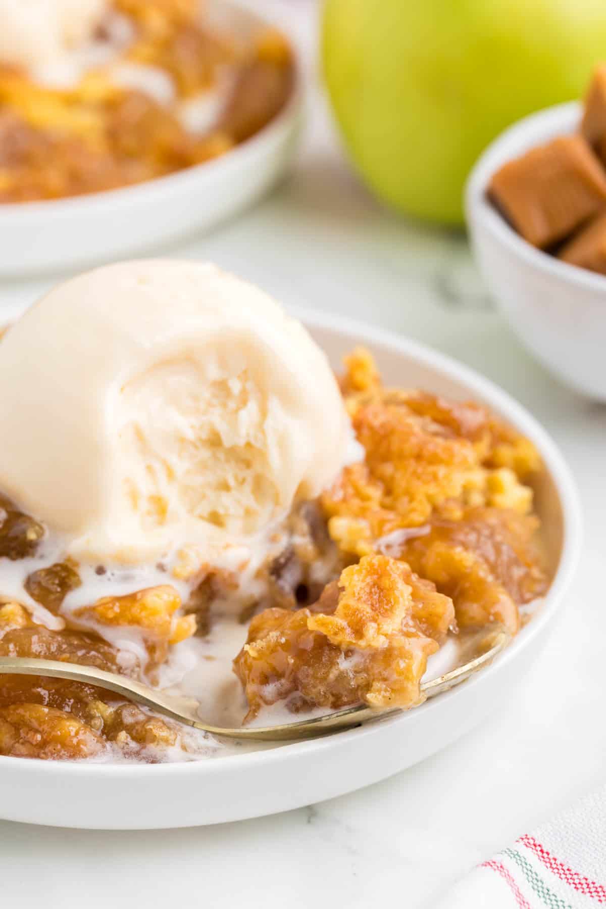 Caramel Apple Dump Cake is an easy and decadent dessert recipe made with apple pie filling, caramel bits, boxed yellow cake mix and butter.