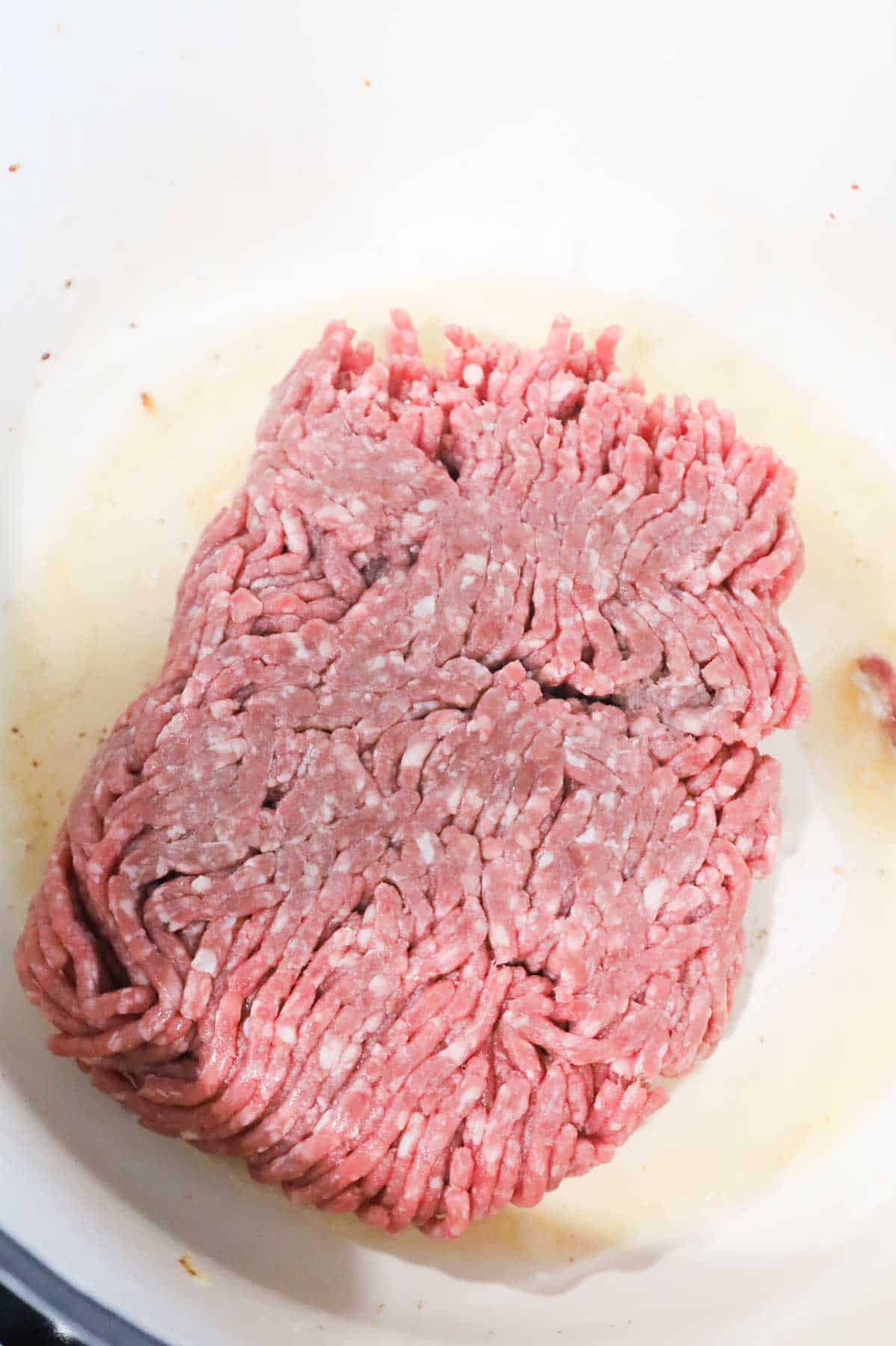 raw ground beef in a Dutch oven with bacon fat