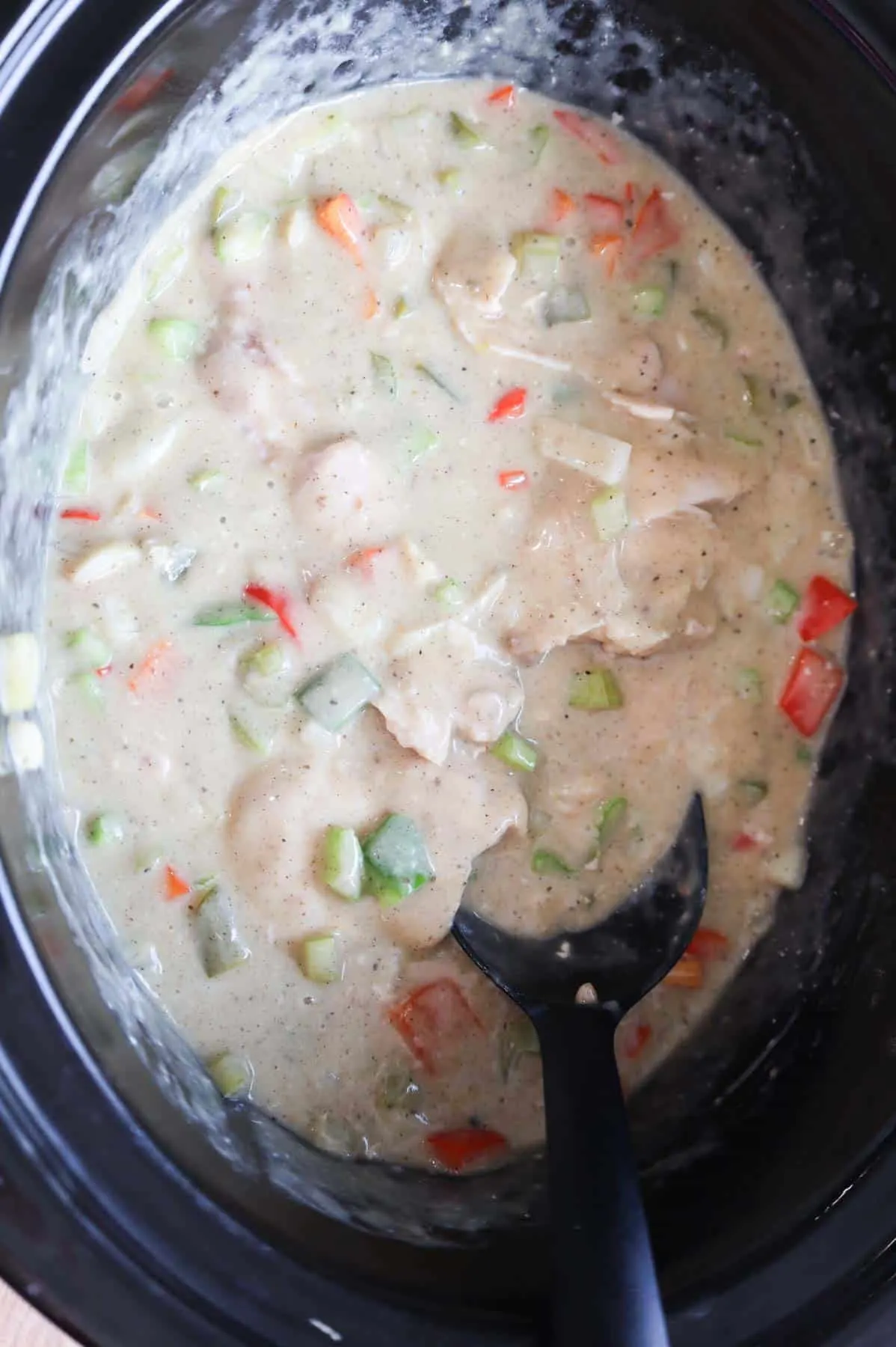 stirring creamy chicken and veggie mixture in a Crock Pot
