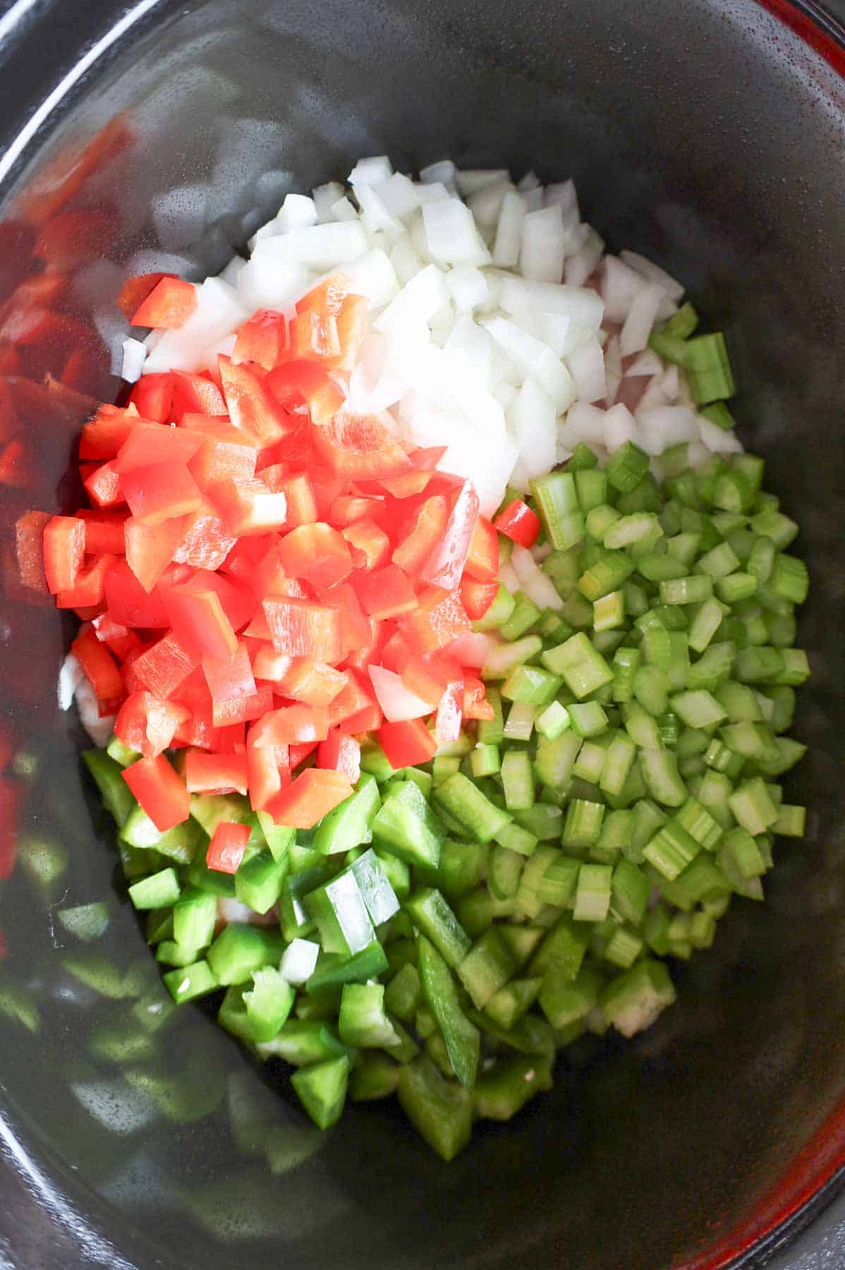 diced onions, celery, red and green bell peppers and chicken thighs in a Crock Pot