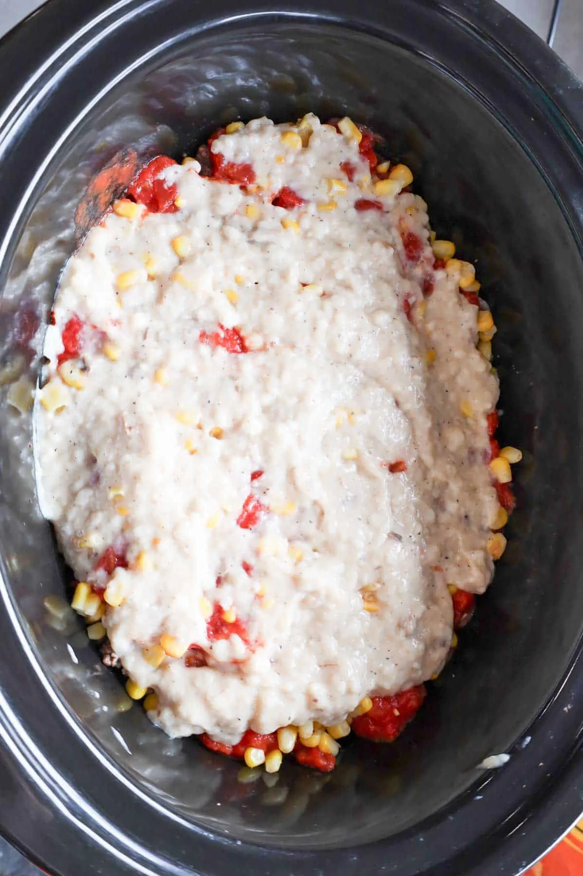 cream of mushroom soup mixture poured over diced tomatoes, corn and ground beef in a slow cooker