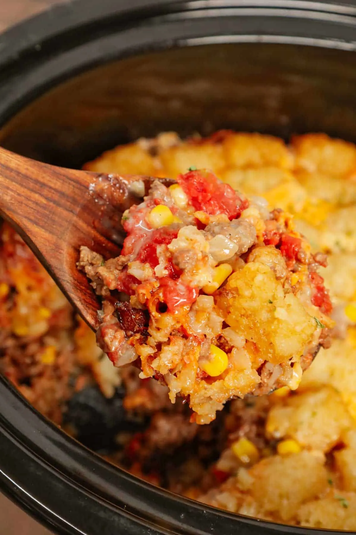 Crock Pot Tater Tot Casserole is a hearty slow cooker dish loaded with ground beef, tater tots, corn, diced tomatoes, cream of mushroom soup and shredded cheddar cheese.