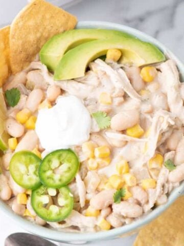 Crock Pot White Chicken Chili is a hearty slow cooker dinner recipe loaded with navy beans, chicken thighs, green chiles, corn, onions and spices.