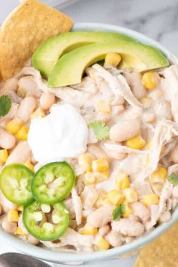 Crock Pot White Chicken Chili is a hearty slow cooker dinner recipe loaded with navy beans, chicken thighs, green chiles, corn, onions and spices.