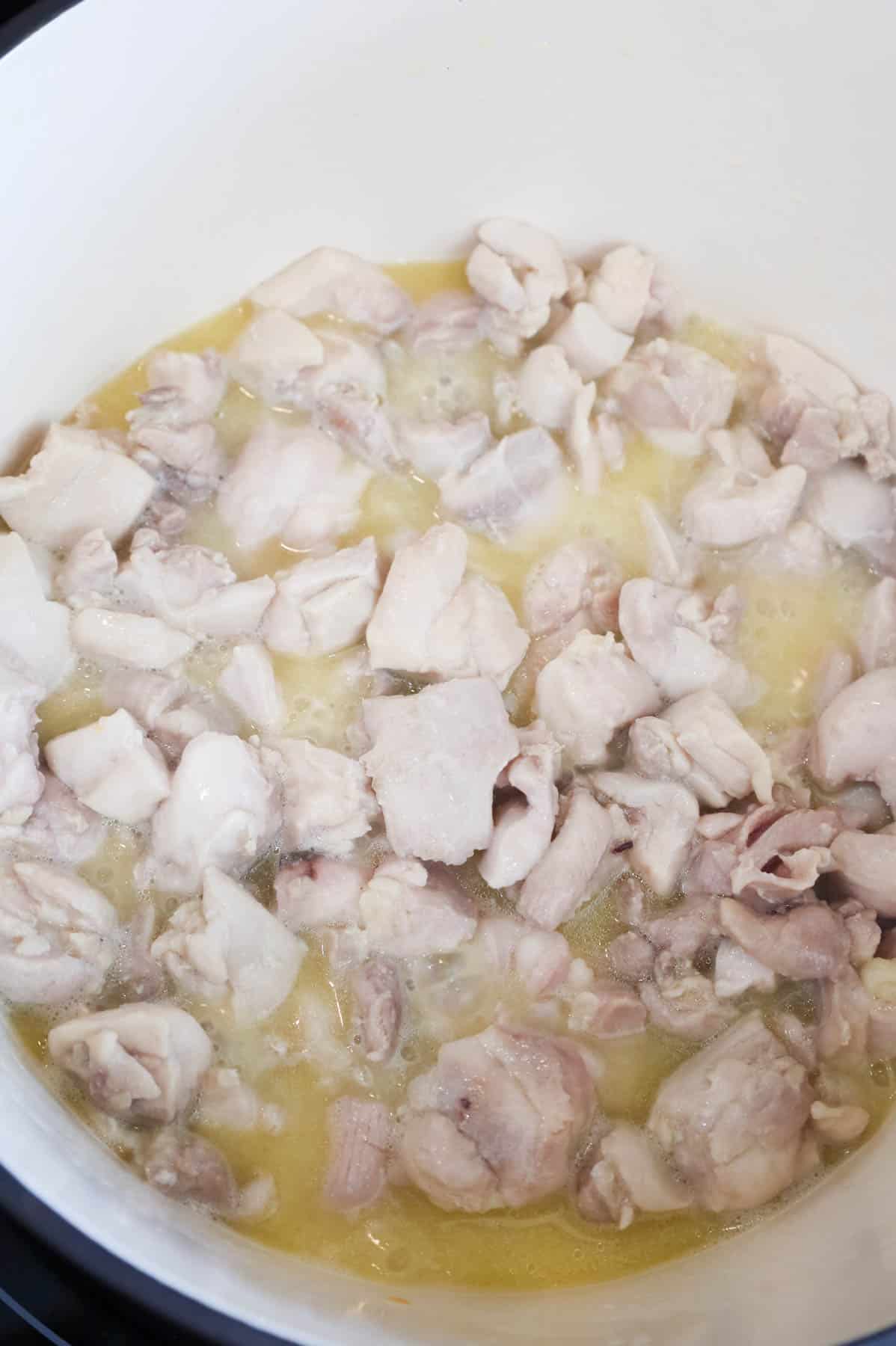 chicken thigh pieces cooking in butter in a Dutch oven