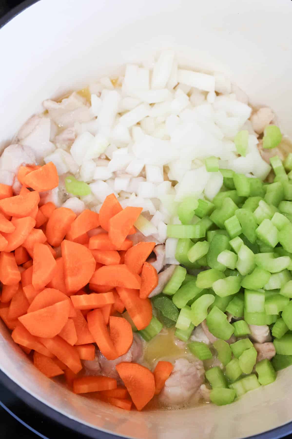 chopped onions, carrots and celery added to Dutch oven with butter and chicken thigh pieces