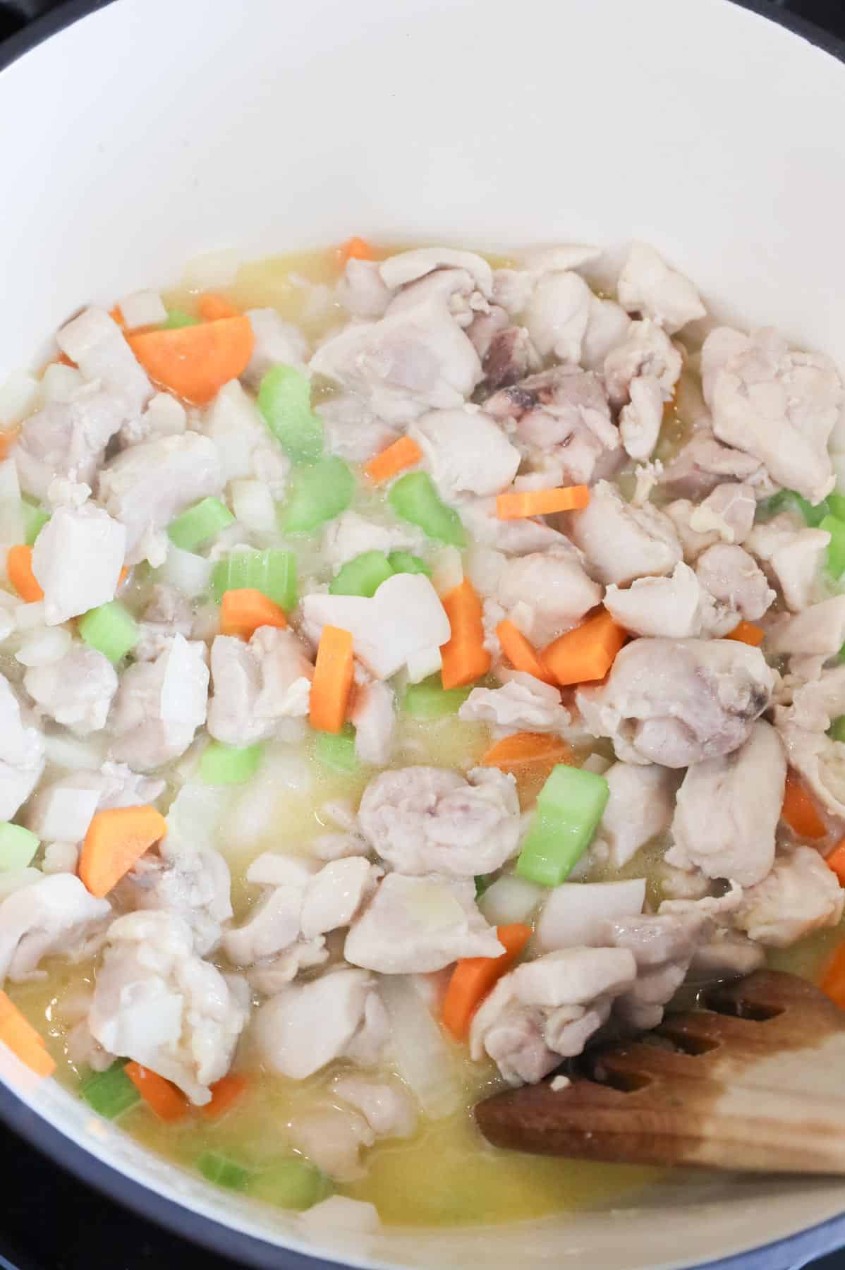 chicken thigh chunks and veggies cooking in a pot