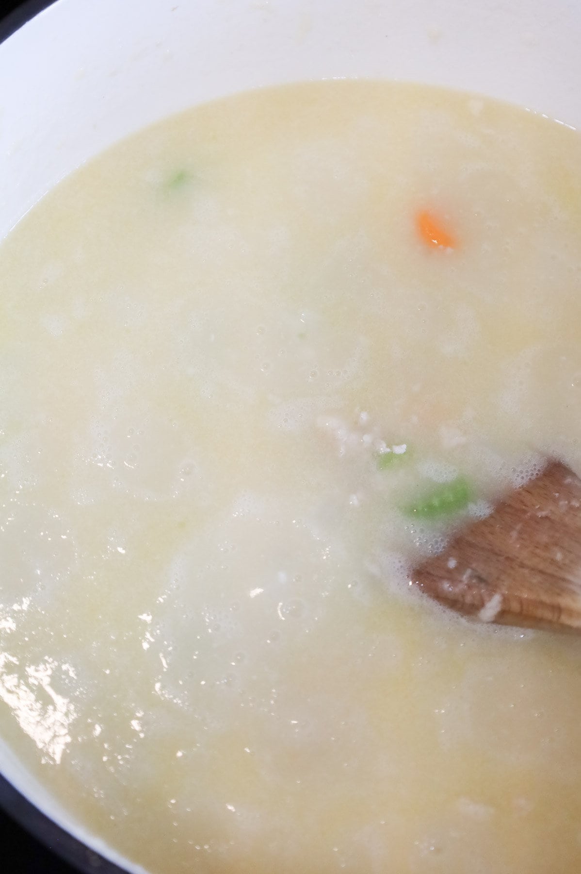 chicken broth and roux mixture being stirred in a pot