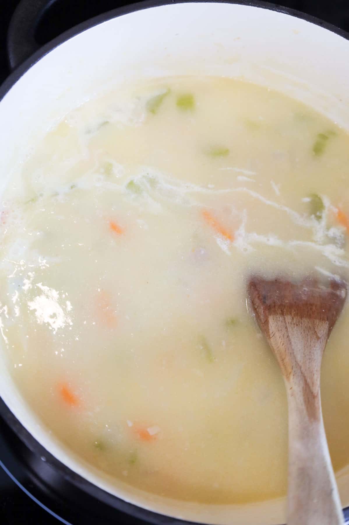 heavy cream poured into broth mixture in a pot