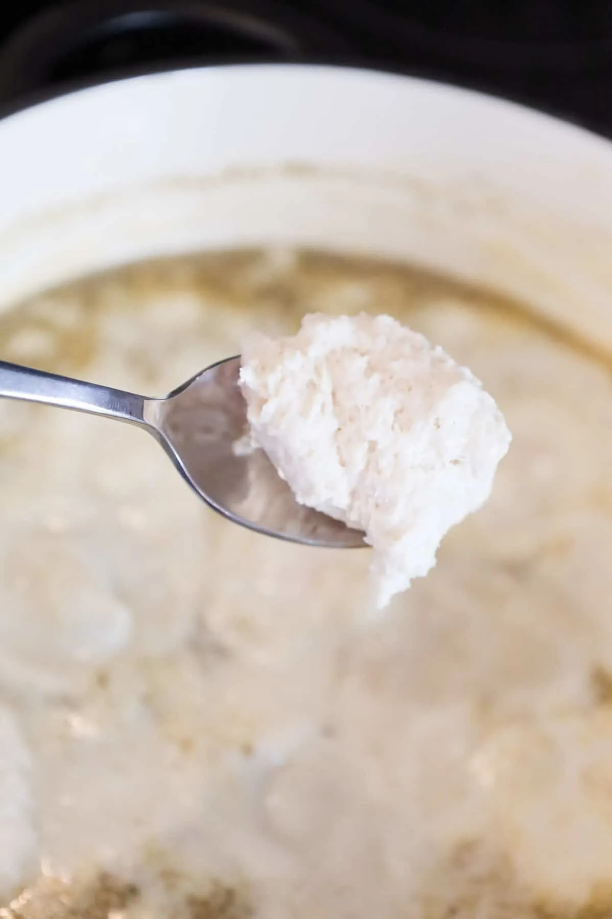 spoon of Bisquick dough being dropped into creamy chicken broth