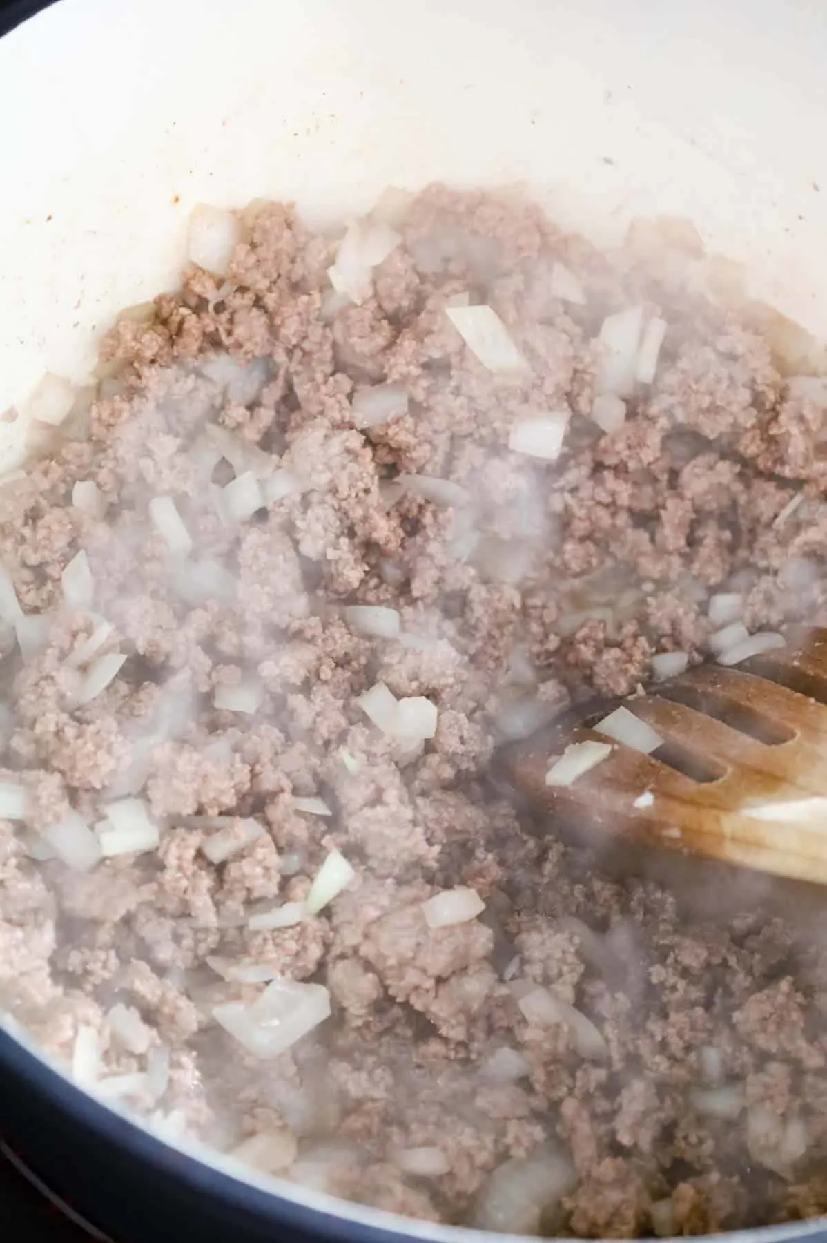 ground beef and diced onions being cooked in a pot