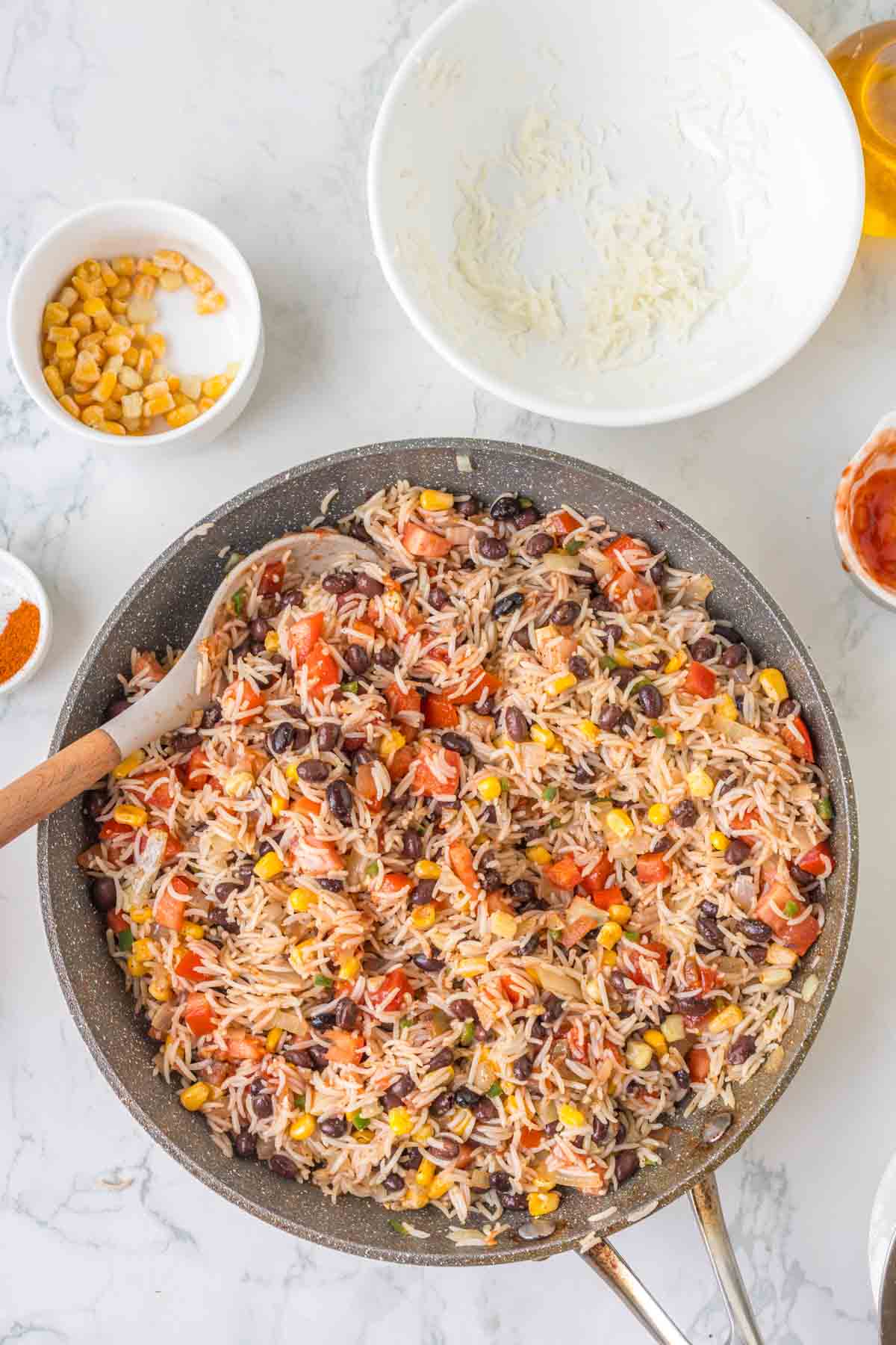 salsa being stirred into fried rice in a skillet