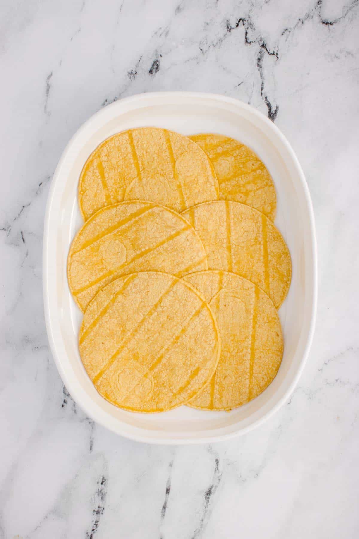 corn tortillas in the bottom of a baking dish