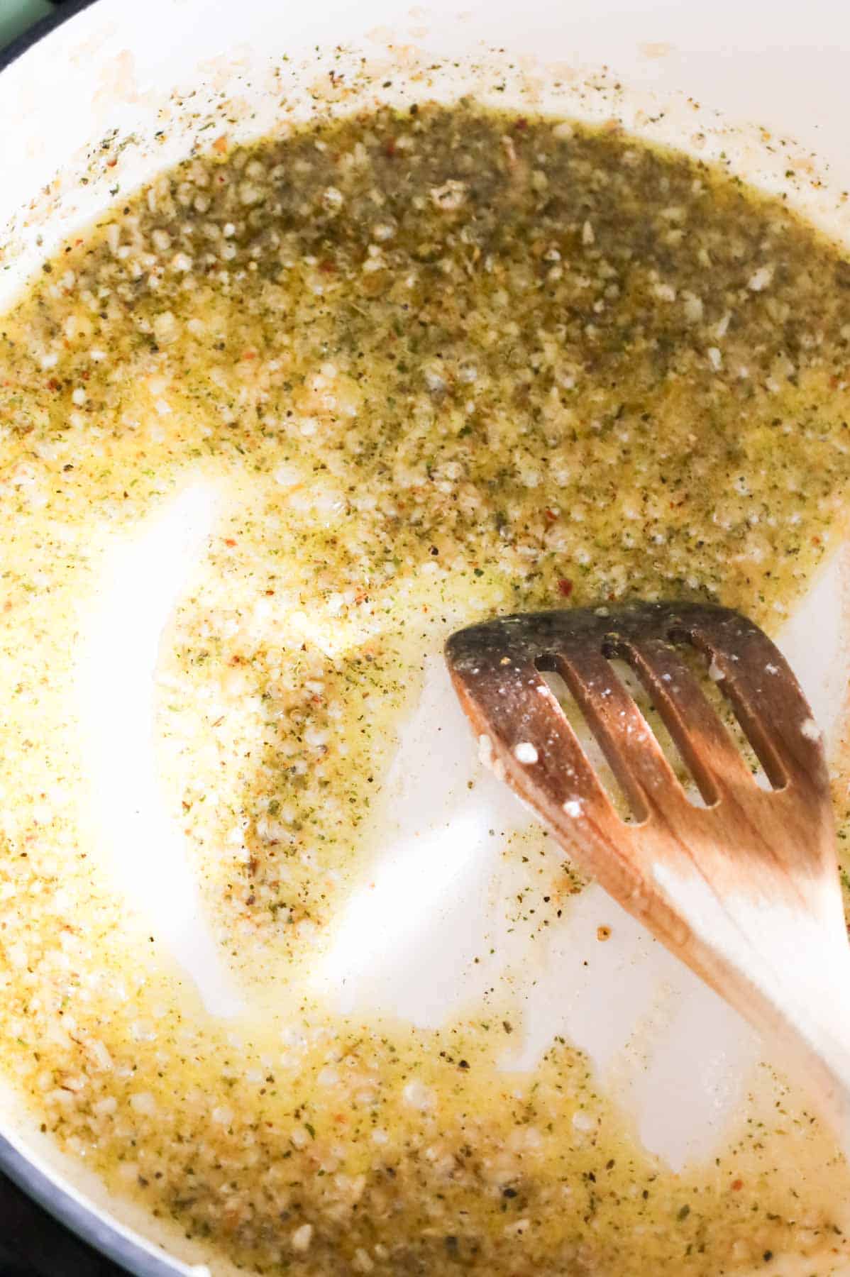 butter and Italian seasoning being stirred in a skillet