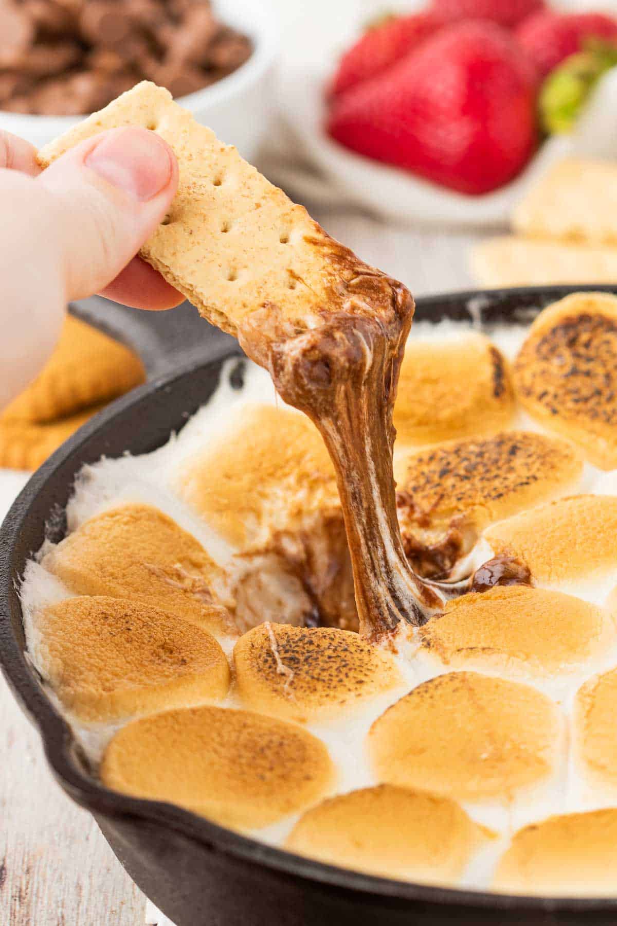 S'mores Dip is a simple and delicious dessert with a base of melted chocolate and topped with gooey toasted marshmallows perfect for scooping up with graham crackers, pretzels, cookies and fresh strawberries.