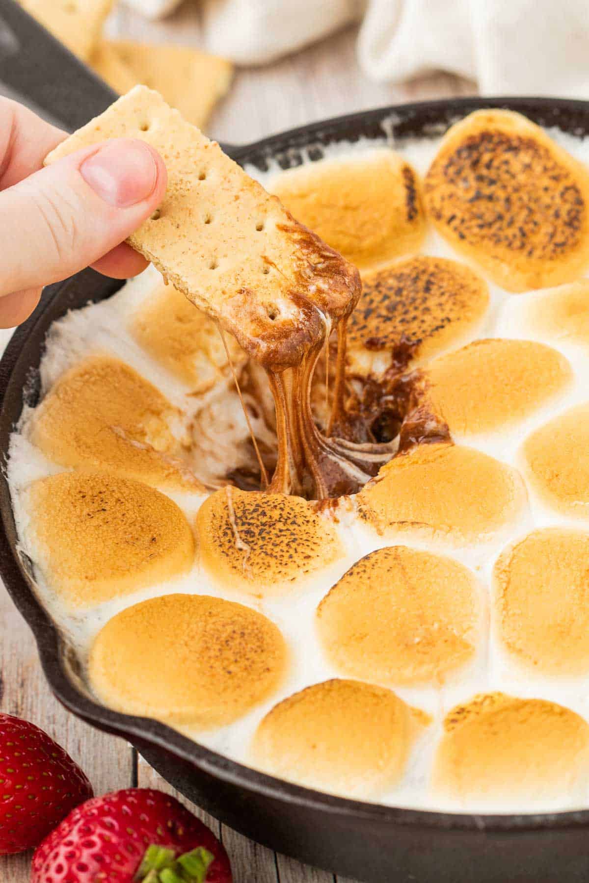 S'mores Dip is a simple and delicious dessert with a base of melted chocolate and topped with gooey toasted marshmallows perfect for scooping up with graham crackers, pretzels, cookies and fresh strawberries.