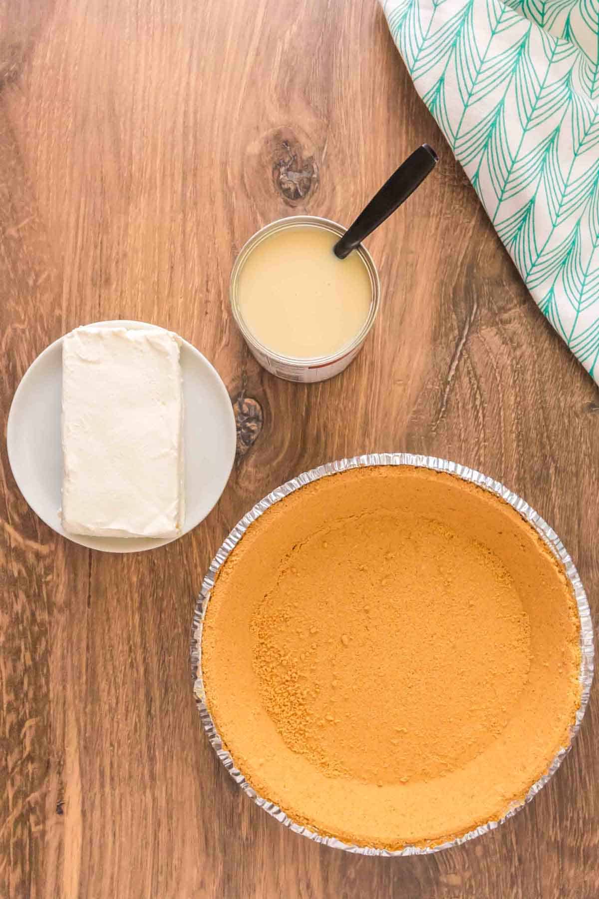 graham pie crust, cream cheese and sweetened condensed milk on the counter