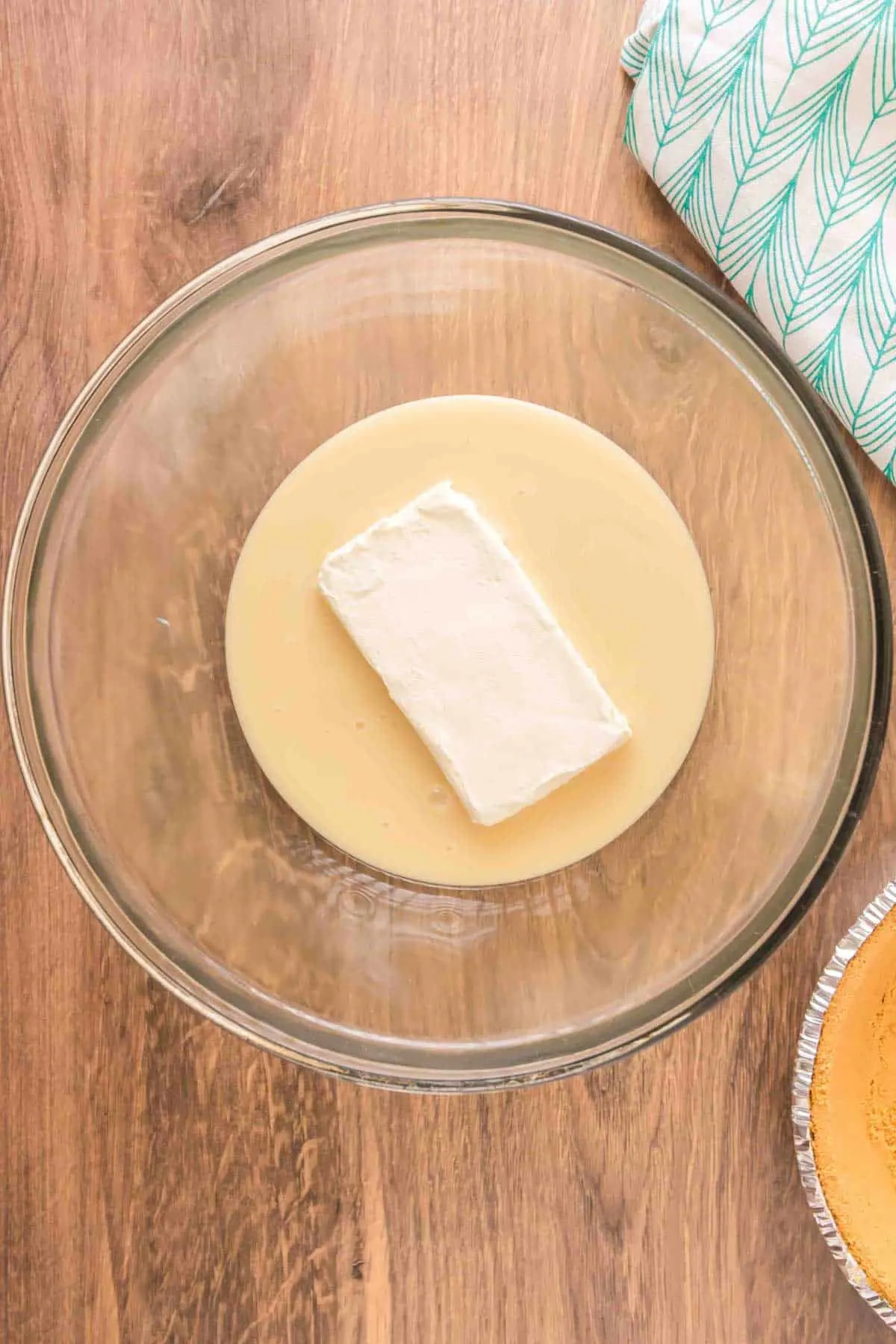 sweetened condensed milk and a brick of cream cheese in a bowl
