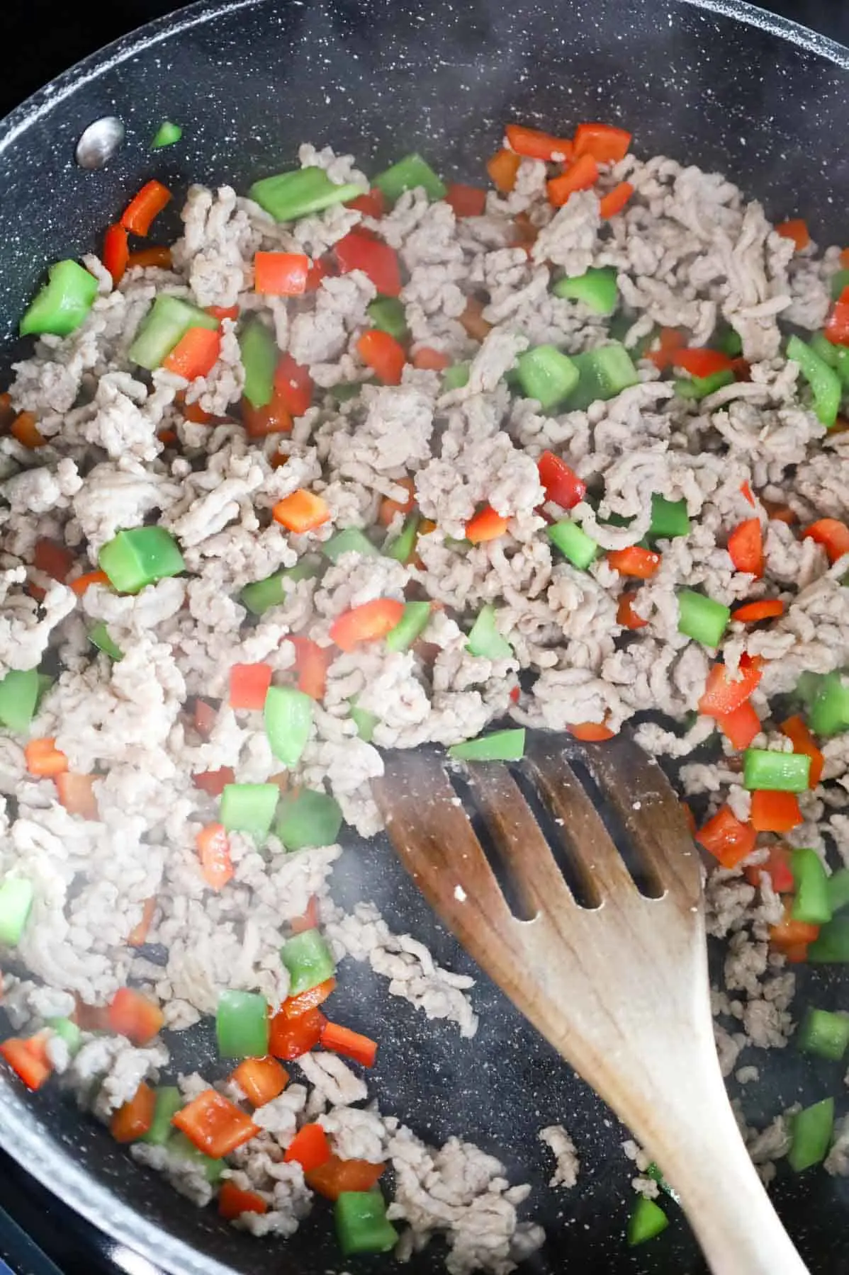 ground chicken and diced red and green bell peppers stirred together in a skillet