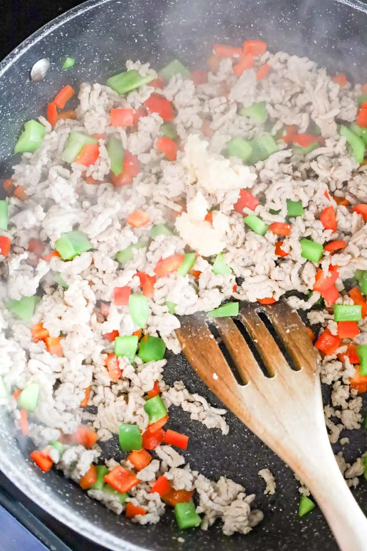 minced garlic added to skillet with cooked ground chicken and diced bell pepper mixture