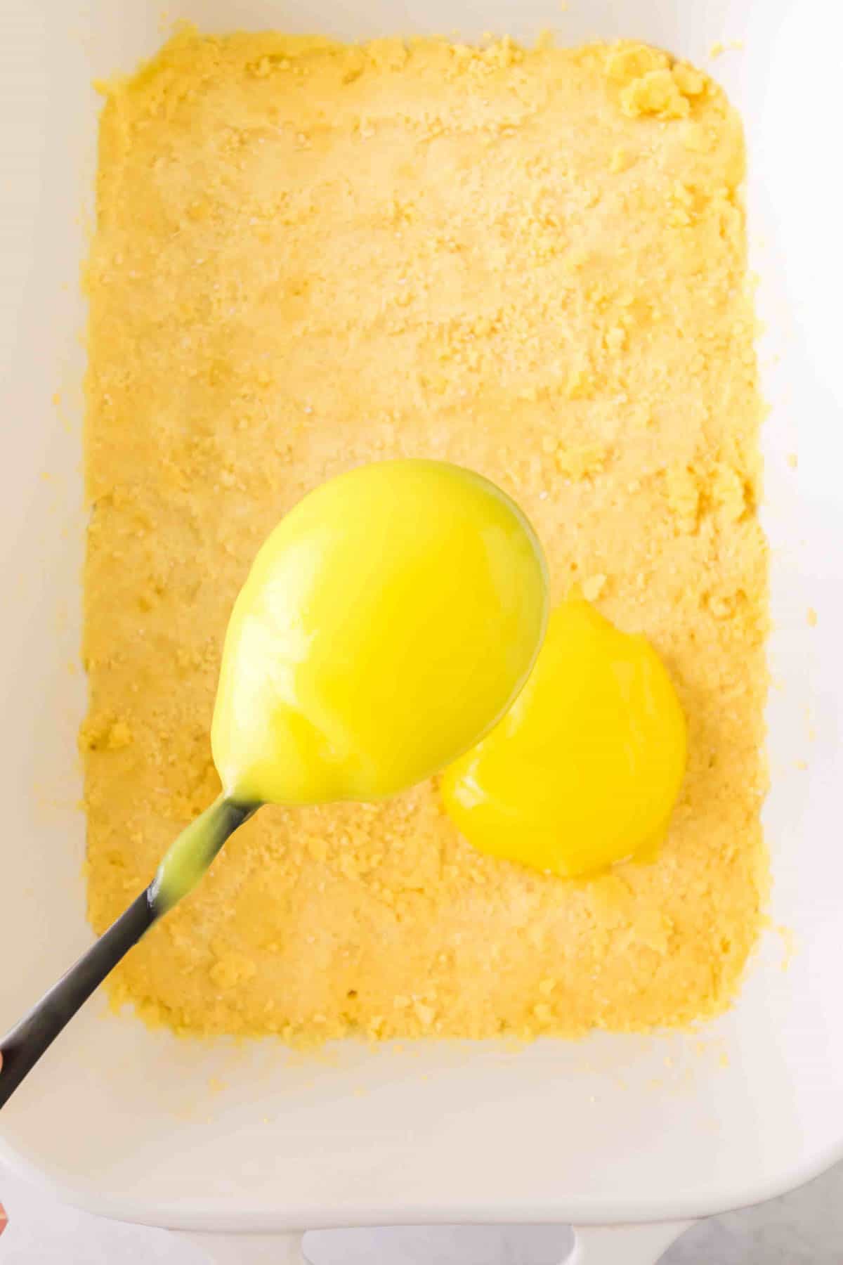 lemon pie filling being spooned over cake mix crust