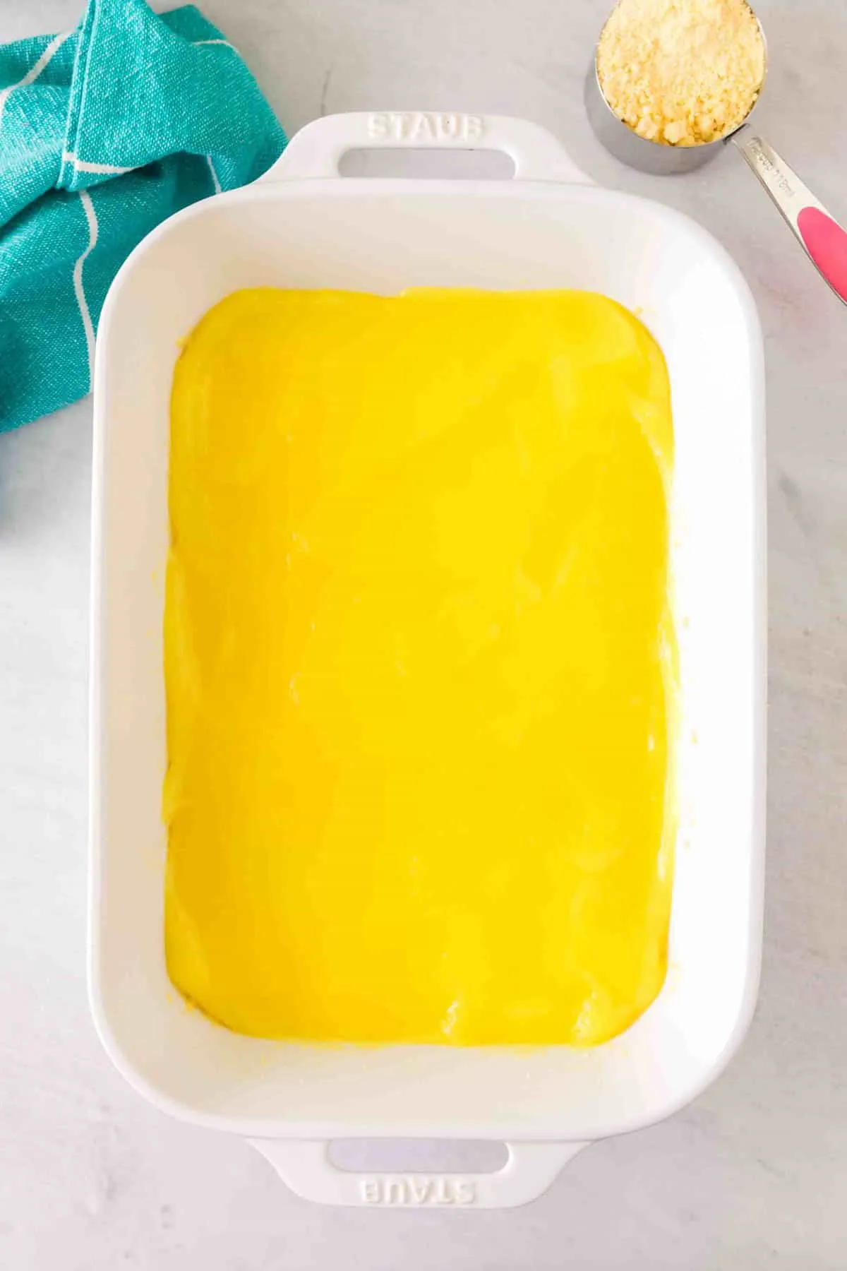 lemon pie filling spread over buttery cake mix crust in a baking dish