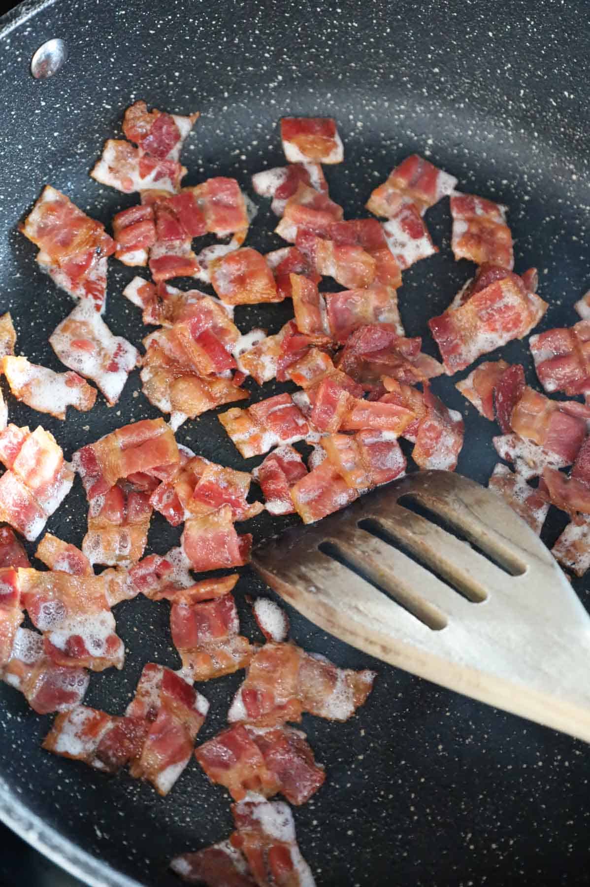 bacon pieces cooking in a skillet