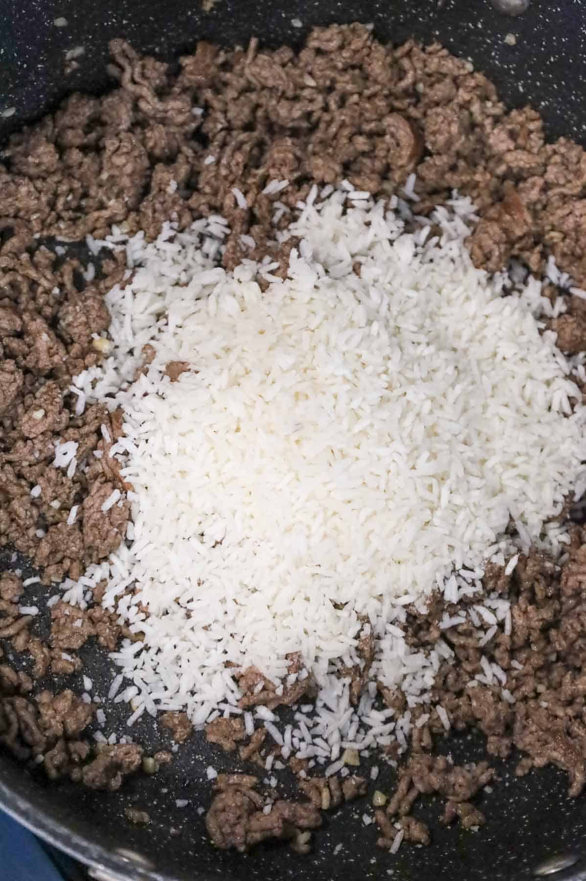 instant rice added to skillet with cooked ground beef