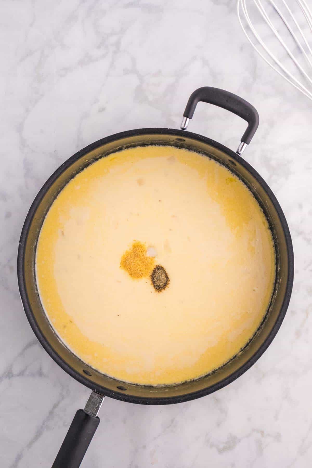 salt, pepper and garlic powder added to cream sauce in a saucepan