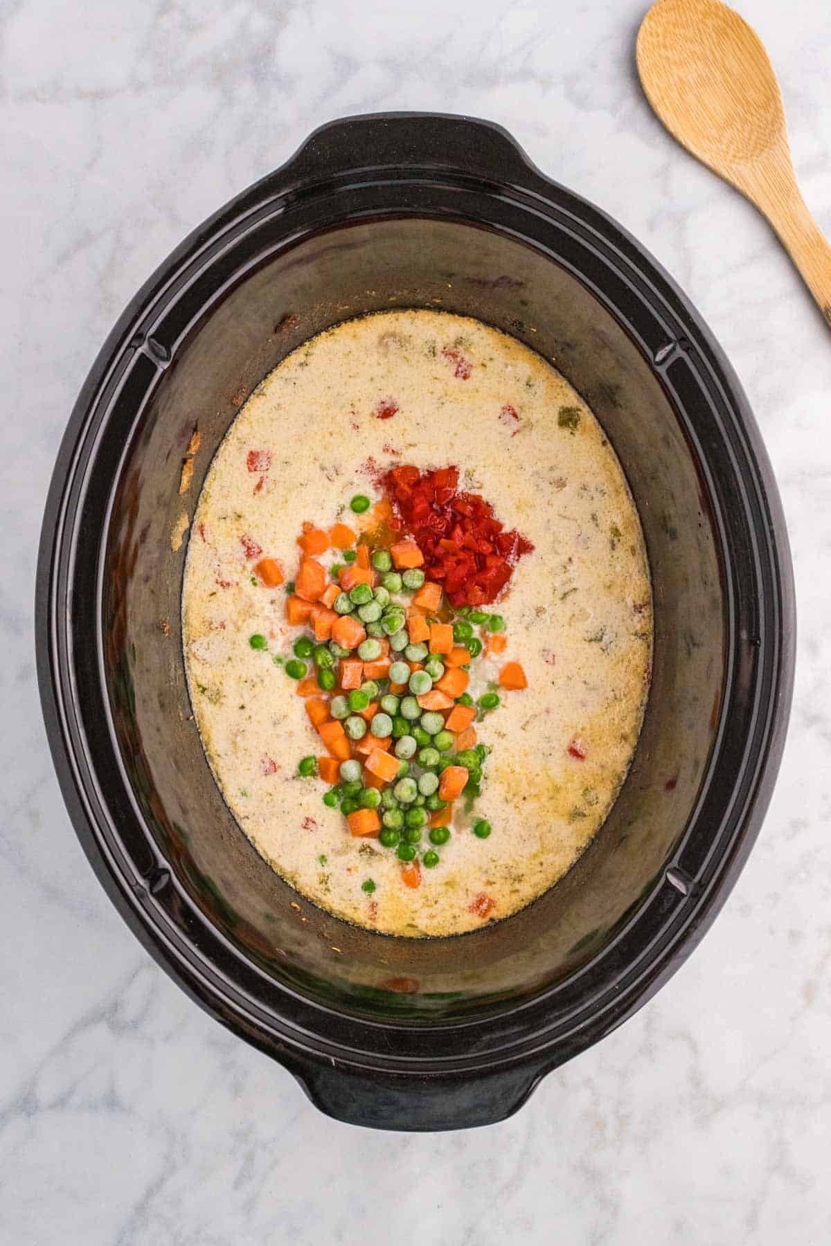 frozen peas and carrots and diced pimentos added to slow cooker with creamy chicken mixture