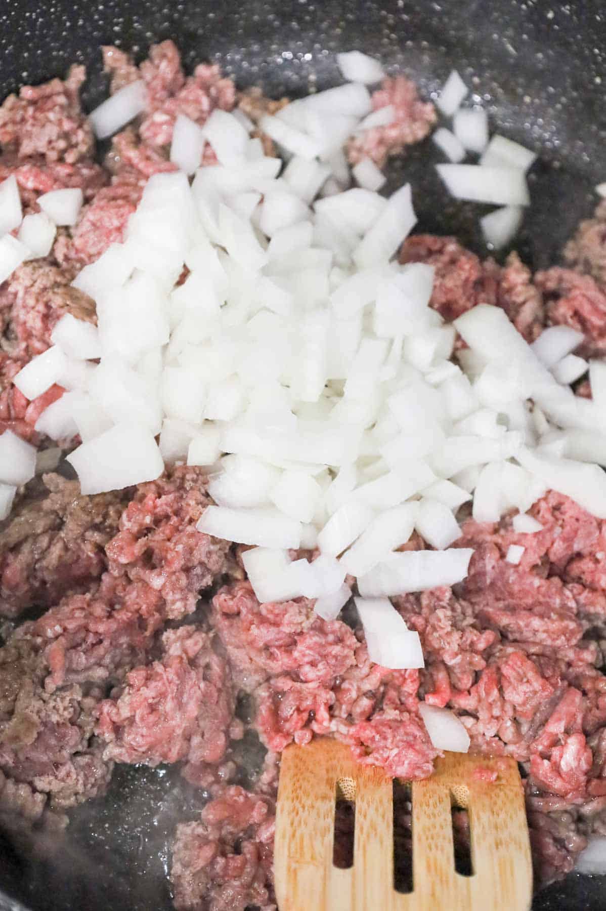 diced onions on top of lean ground beef in a skillet