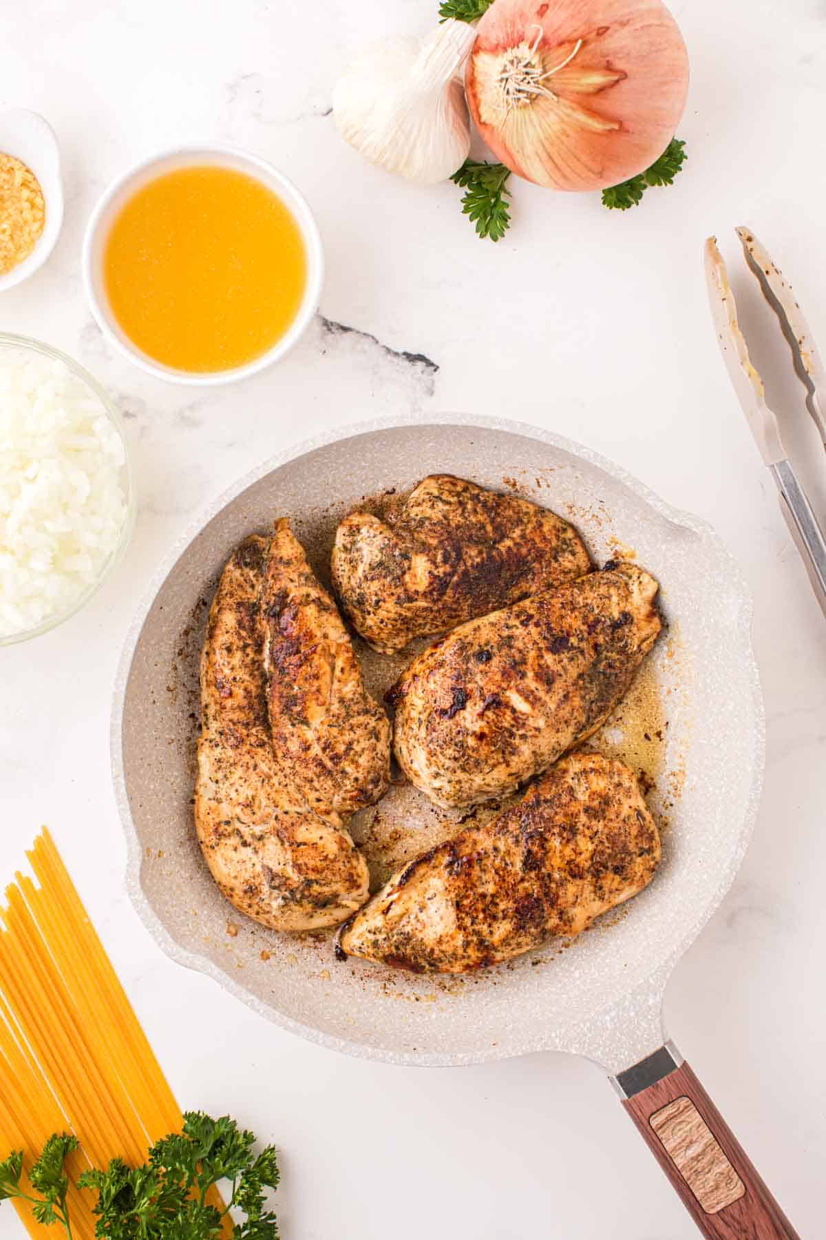 seasoned chicken breasts cooking in a skillet