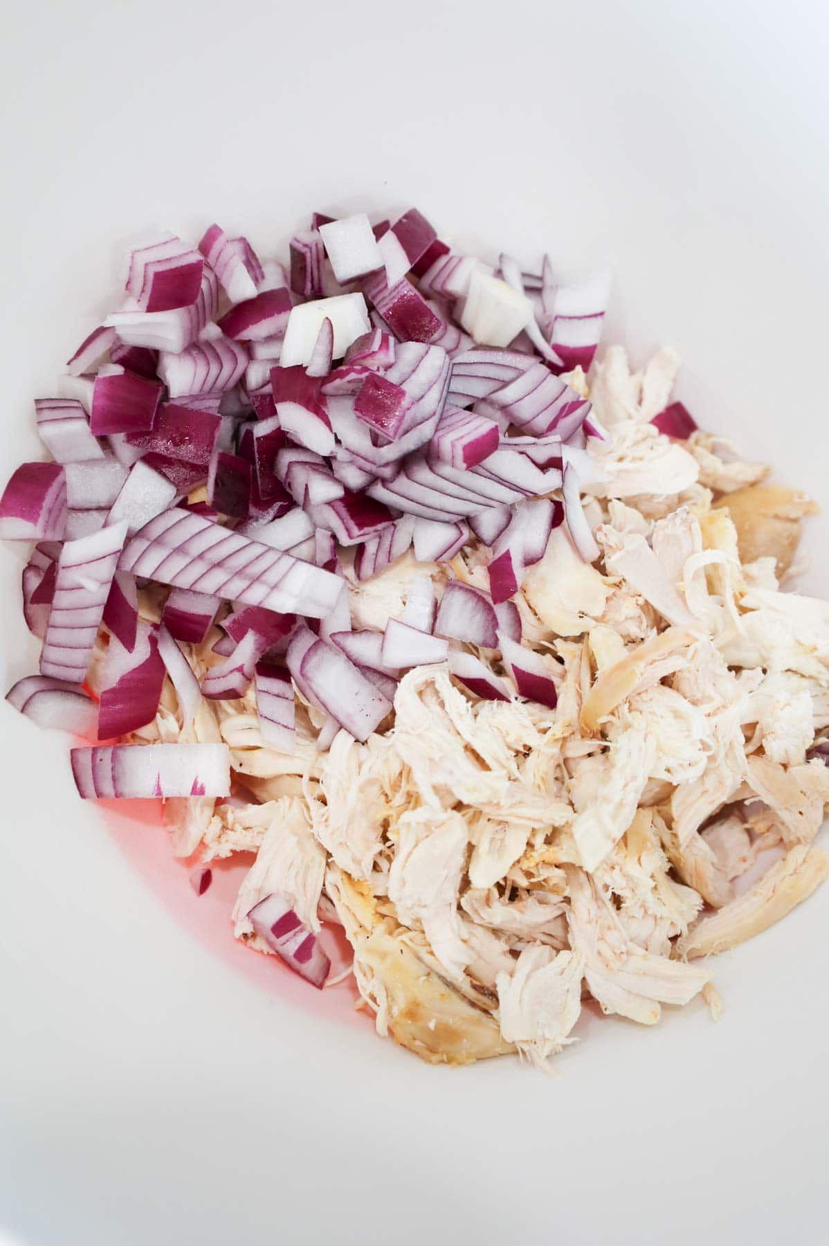 diced red onions and shredded chicken in a bowl