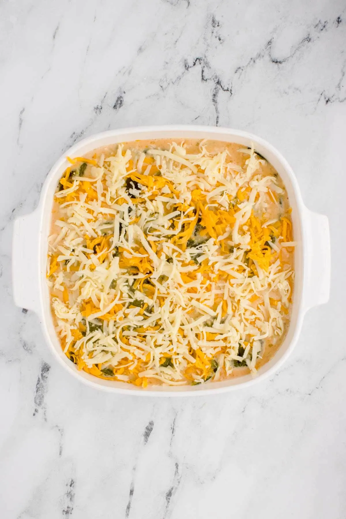 shredded cheese on top of chili relleno casserole in a baking dish