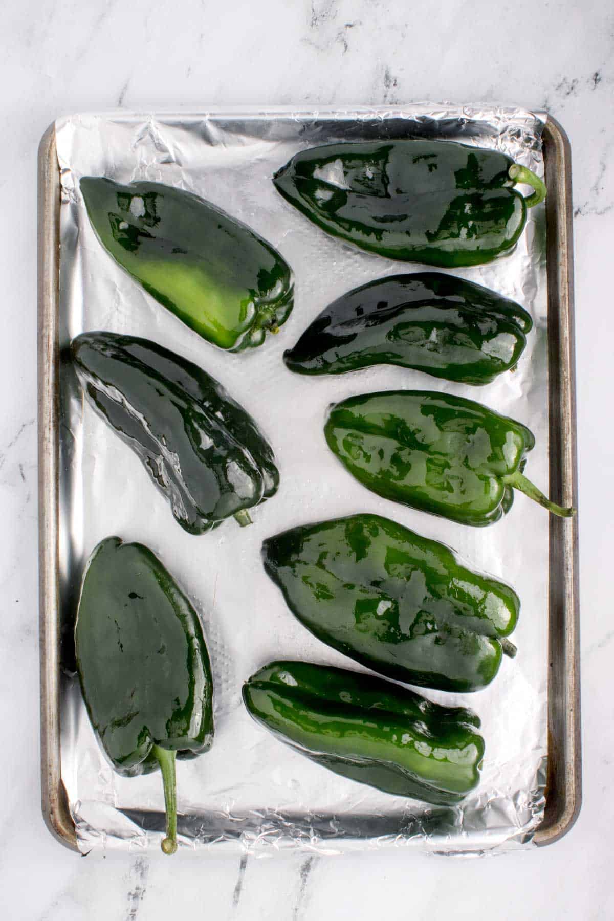 poblano peppers on a foil lined baking sheet