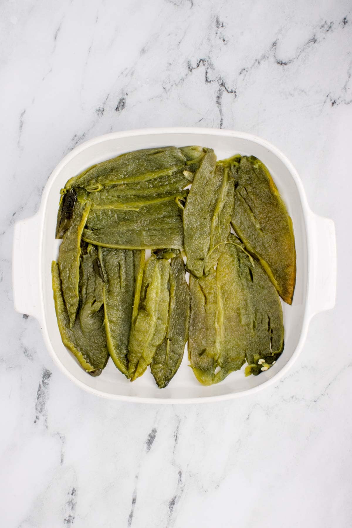 roasted poblano peppers in the bottom of a baking dish