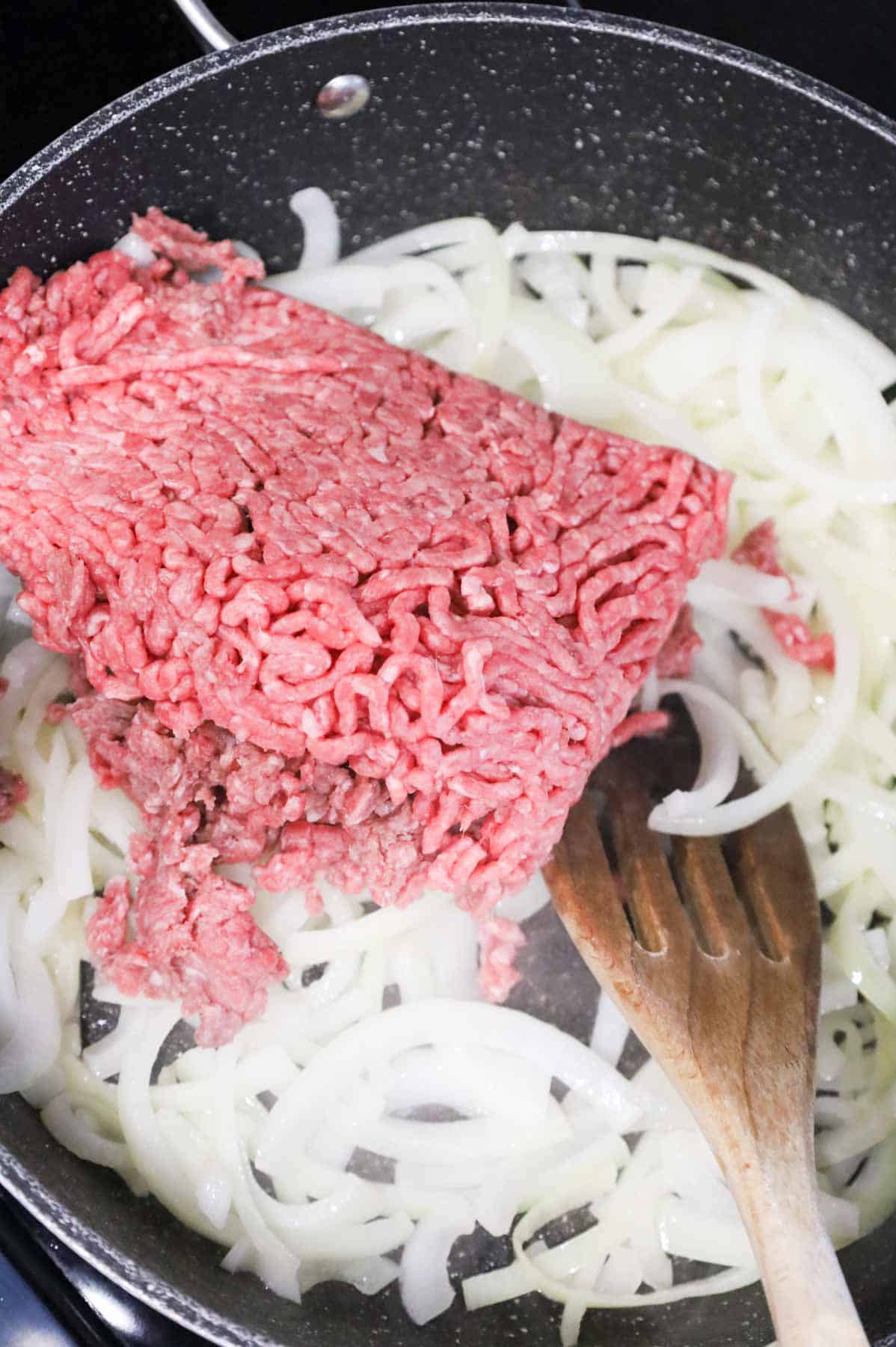 ground beef added to skillet with sliced onions