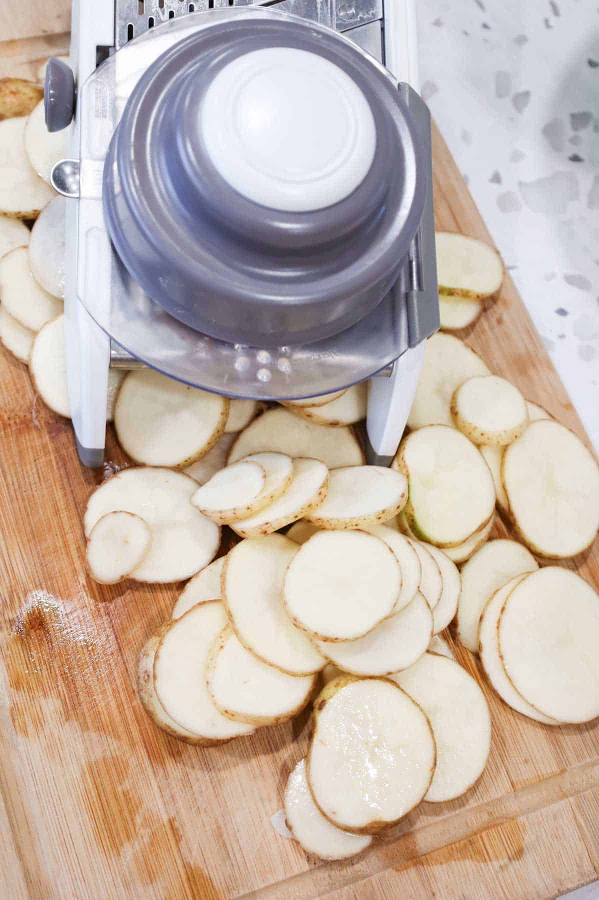 mandoline slicer and sliced potatoes on a cutting board