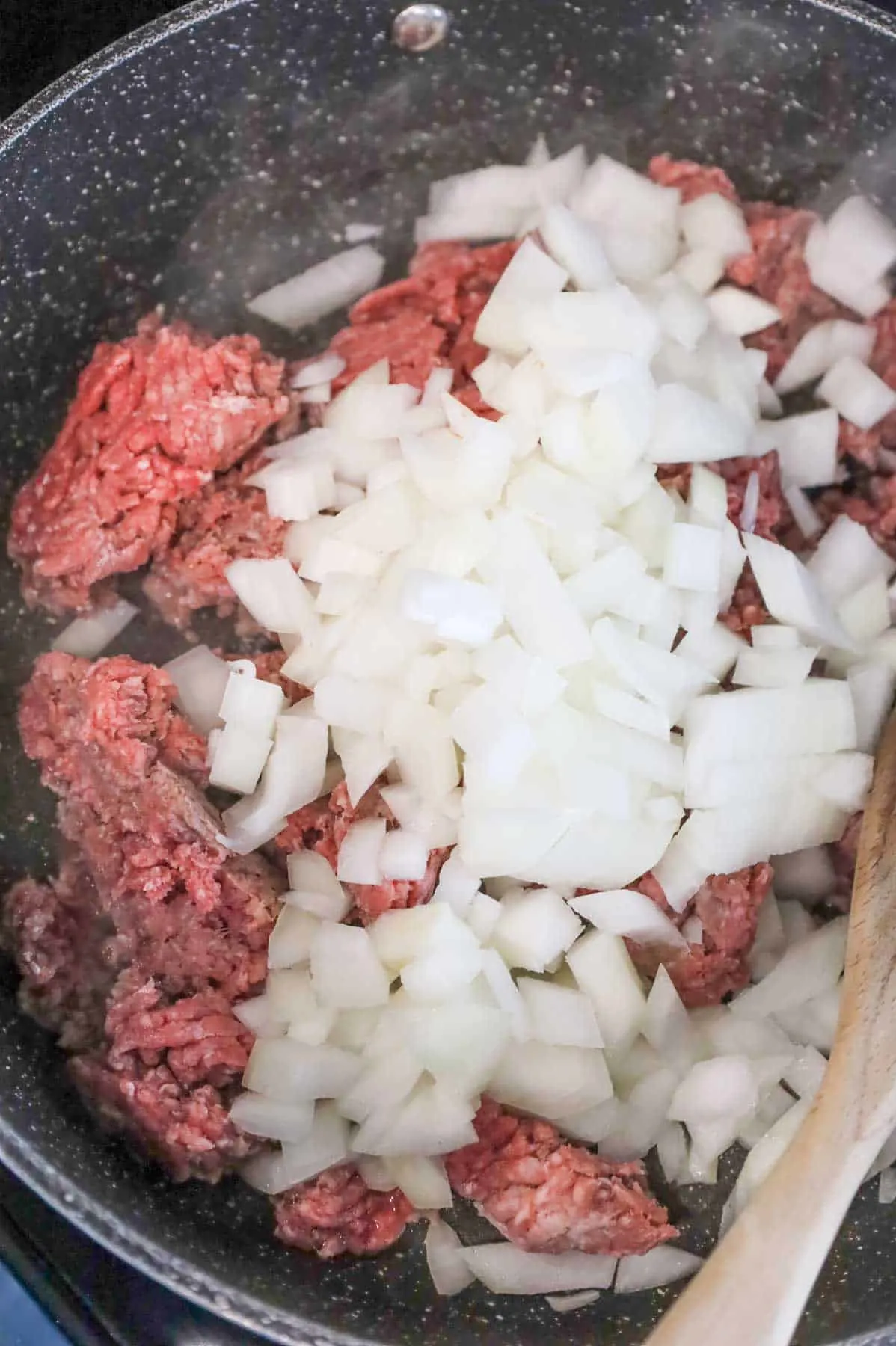 diced onions on top of lean ground beef in a skillet
